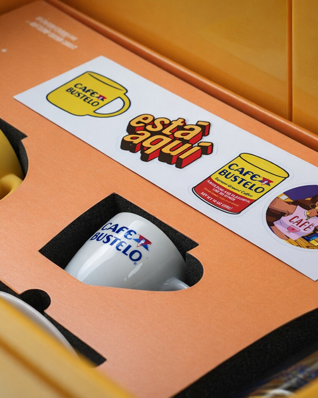 Café Bustelo espresso cup and sticker sheet nested in the orange mailer insert