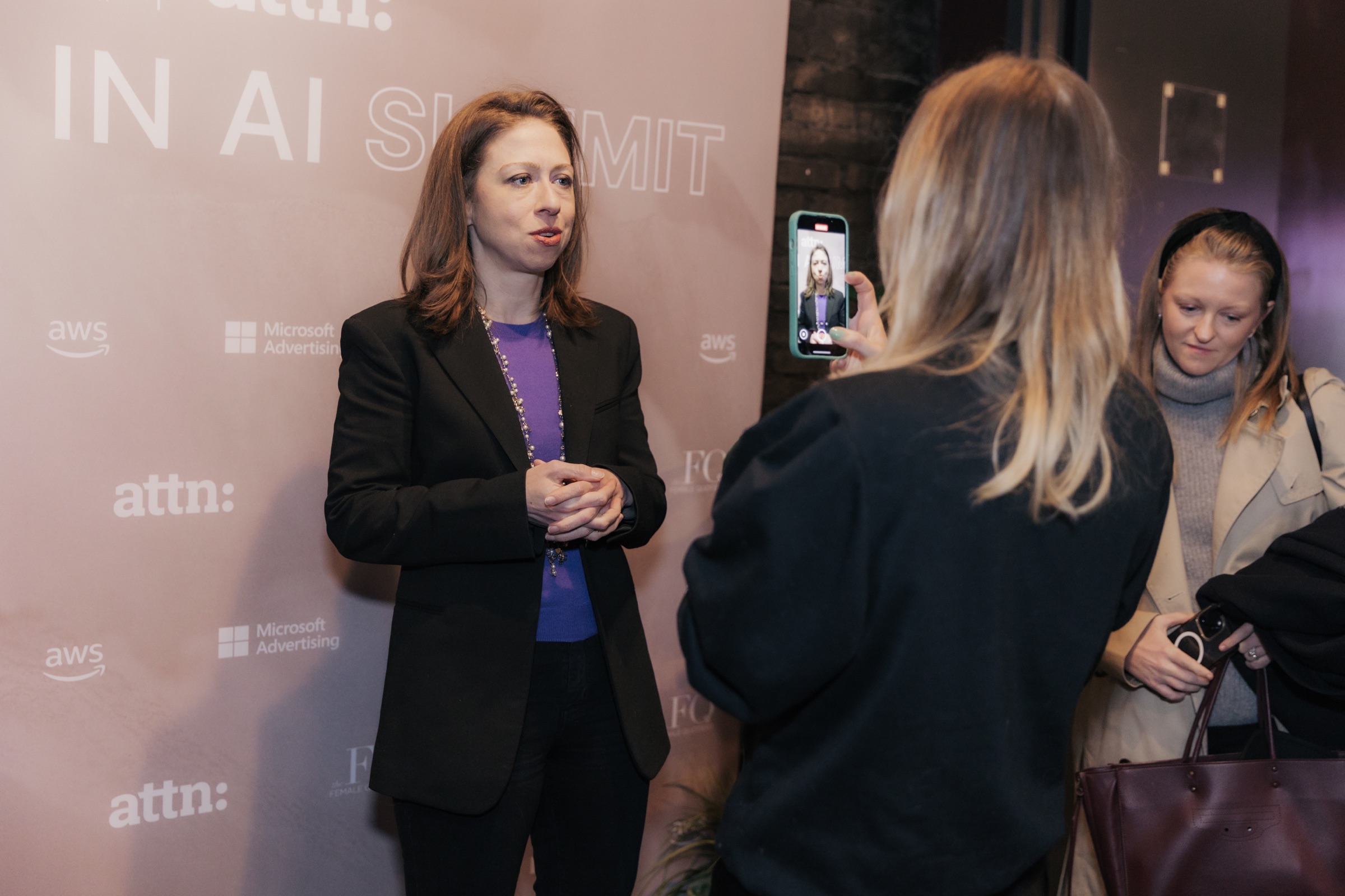 Guest interview in front of the Women in AI Summit sponsor wall