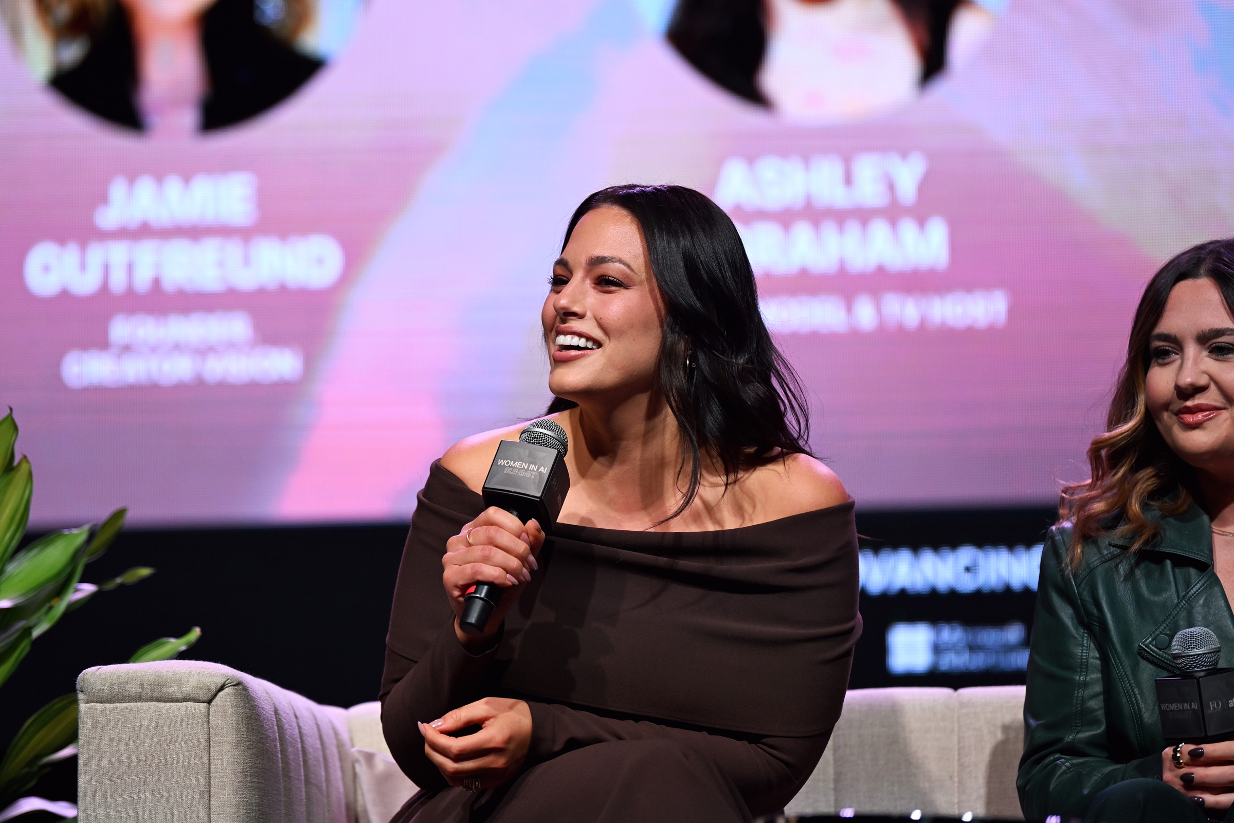 Women in AI Summit speaker holding a branded microphone on stage
