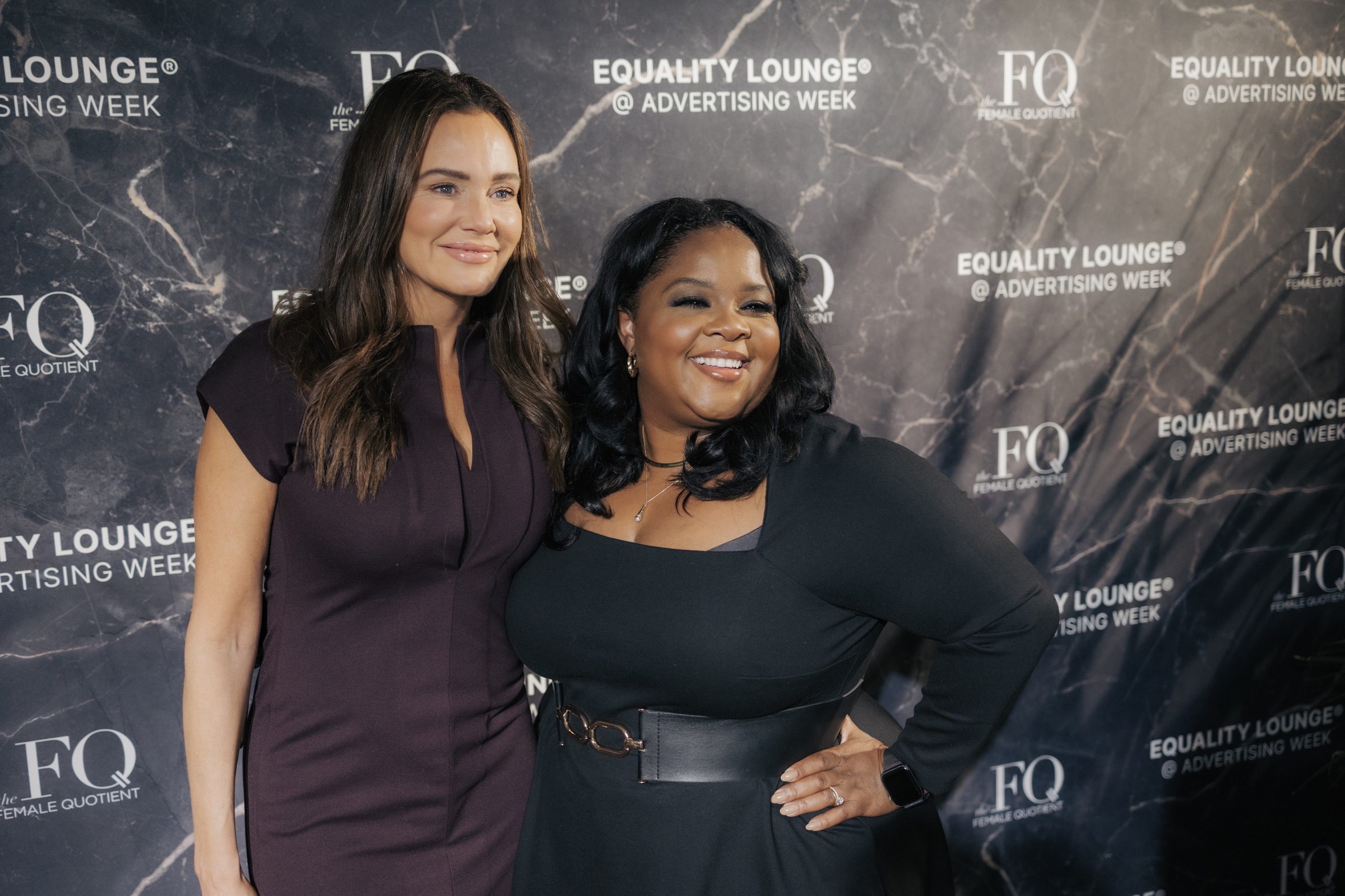Guests posing against the Equality Lounge marble step-and-repeat wall