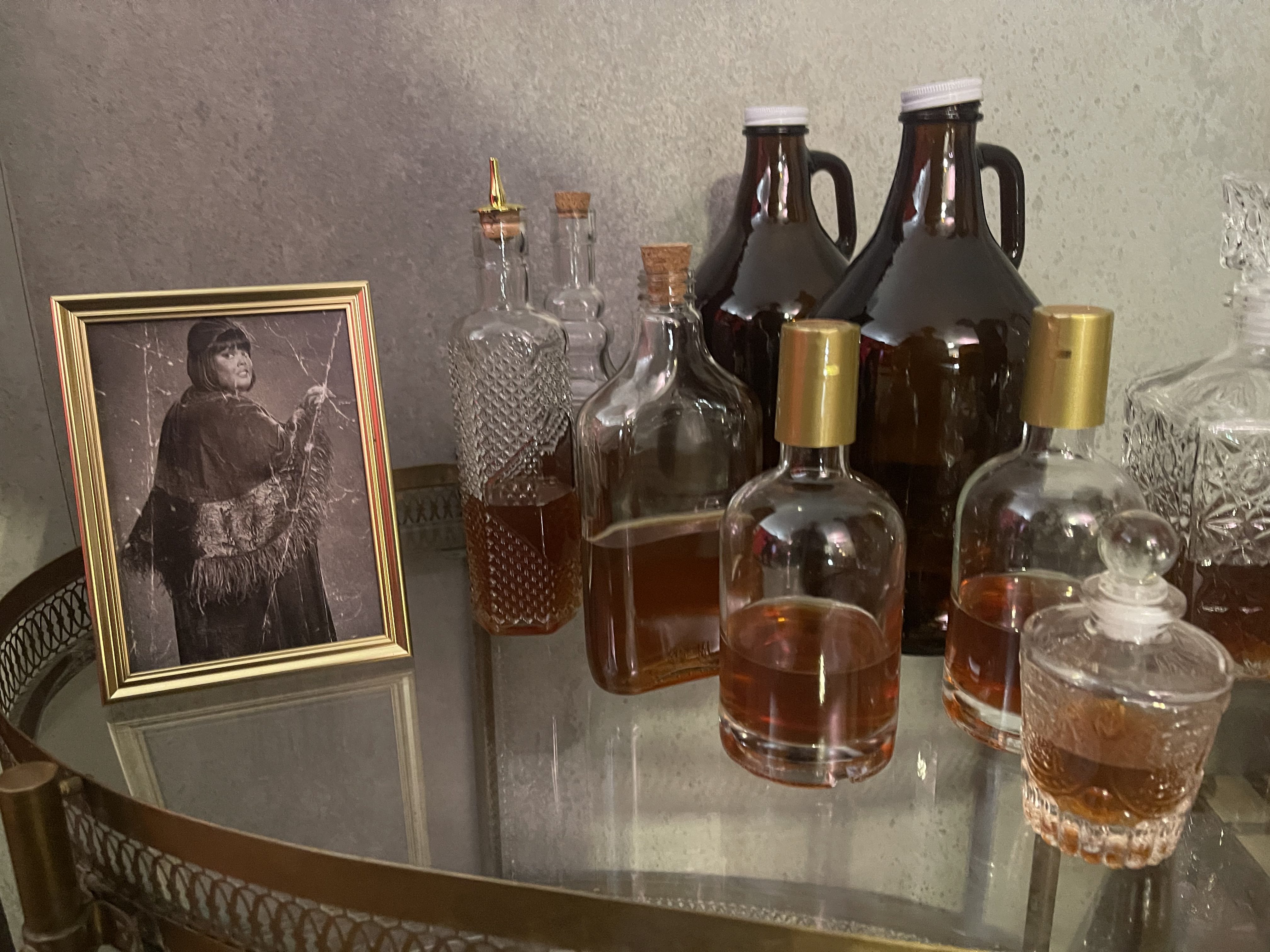 Period bar display with framed Alberta portrait and vintage bottles