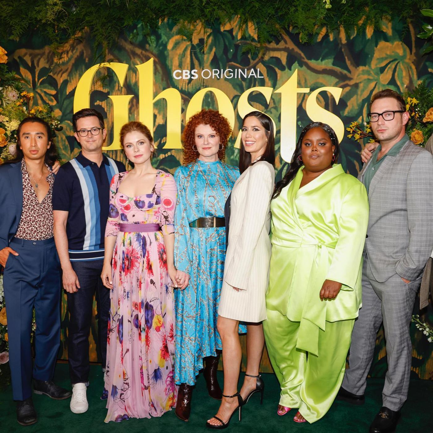 The cast of Ghosts on the green carpet at the floral CBS Original backdrop