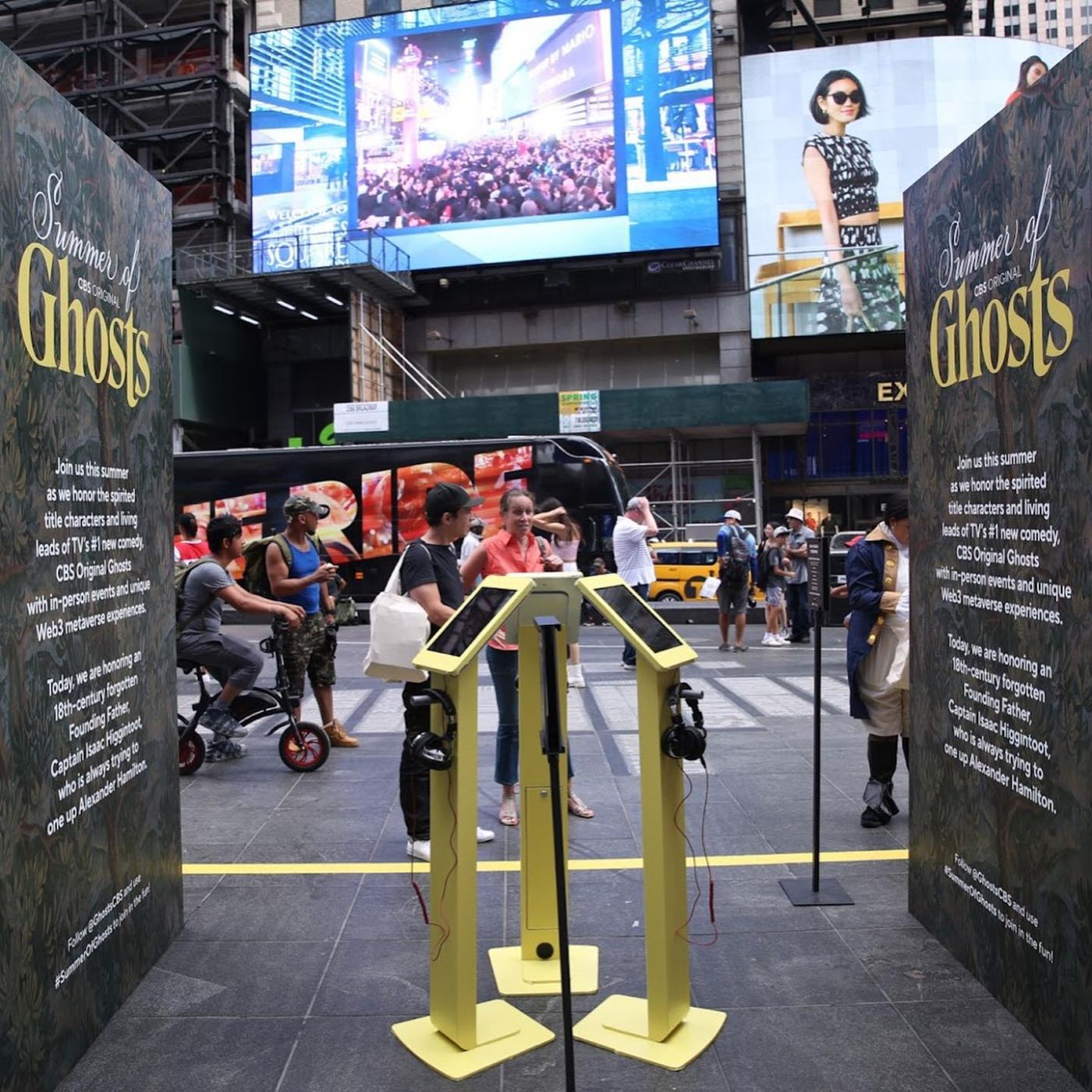 Yellow listening kiosks between Summer of Ghosts tapestry walls in Times Square