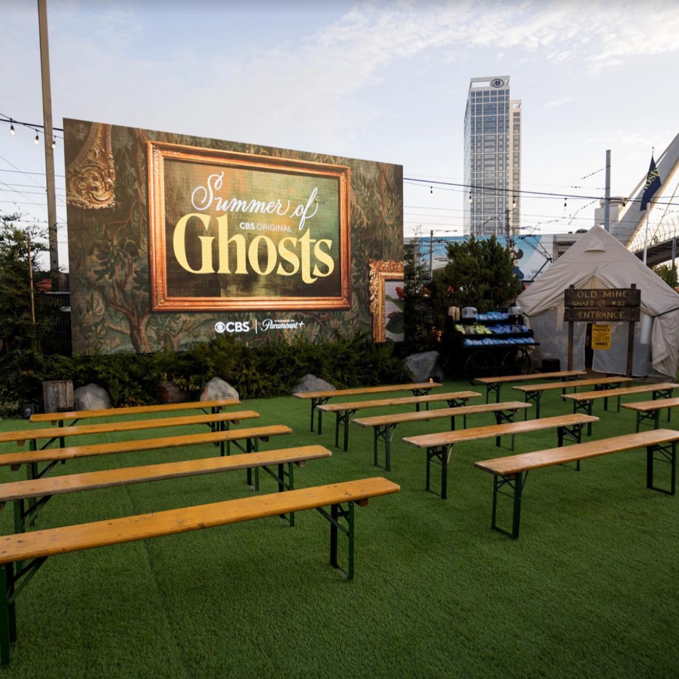 Camp benches facing the Summer of Ghosts screen with popcorn cart and mine-shaft tent