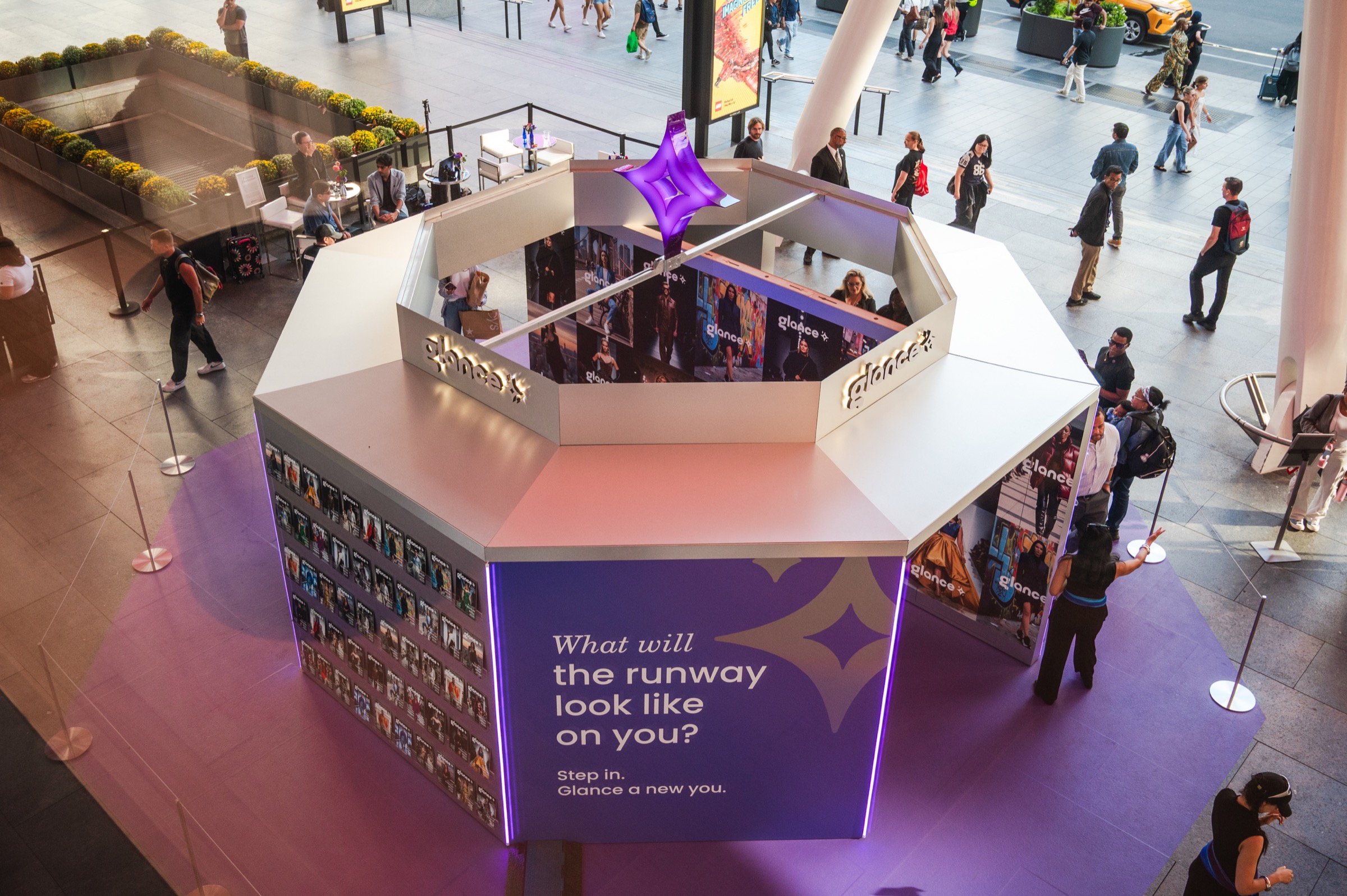 Elevated view of the Glance AI fashion newsstand and guests in Bustle Plaza during New York Fashion Week