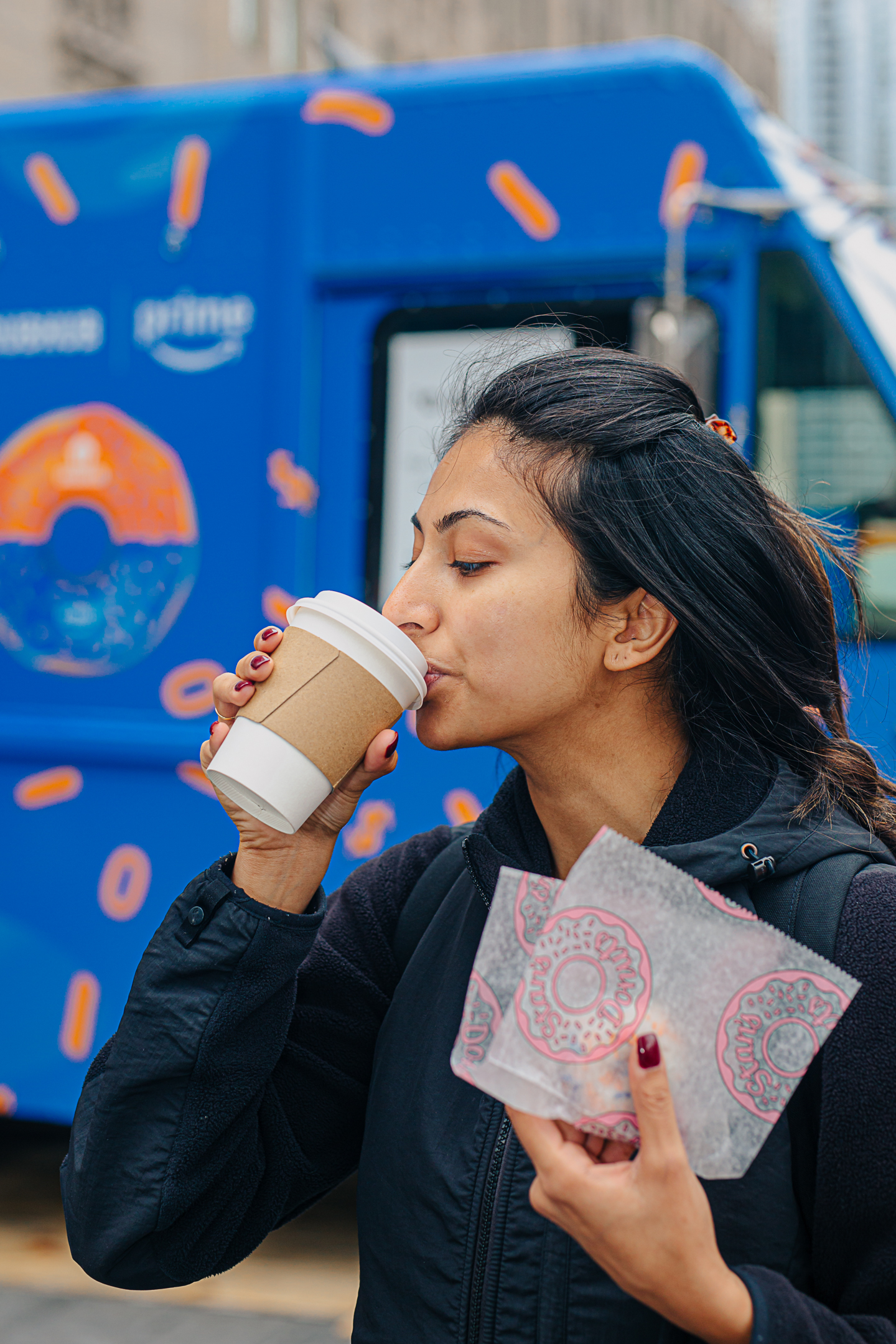 Guest sipping a branded coffee in front of the wrapped truck