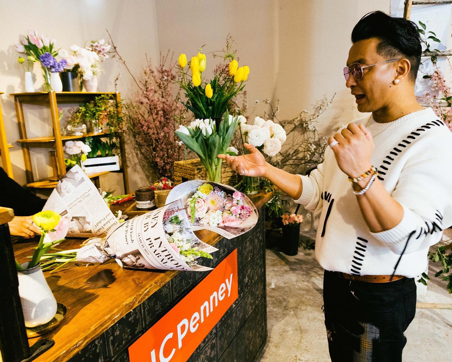 A guest receiving a newspaper-wrapped bouquet at the JCPenney flower bar