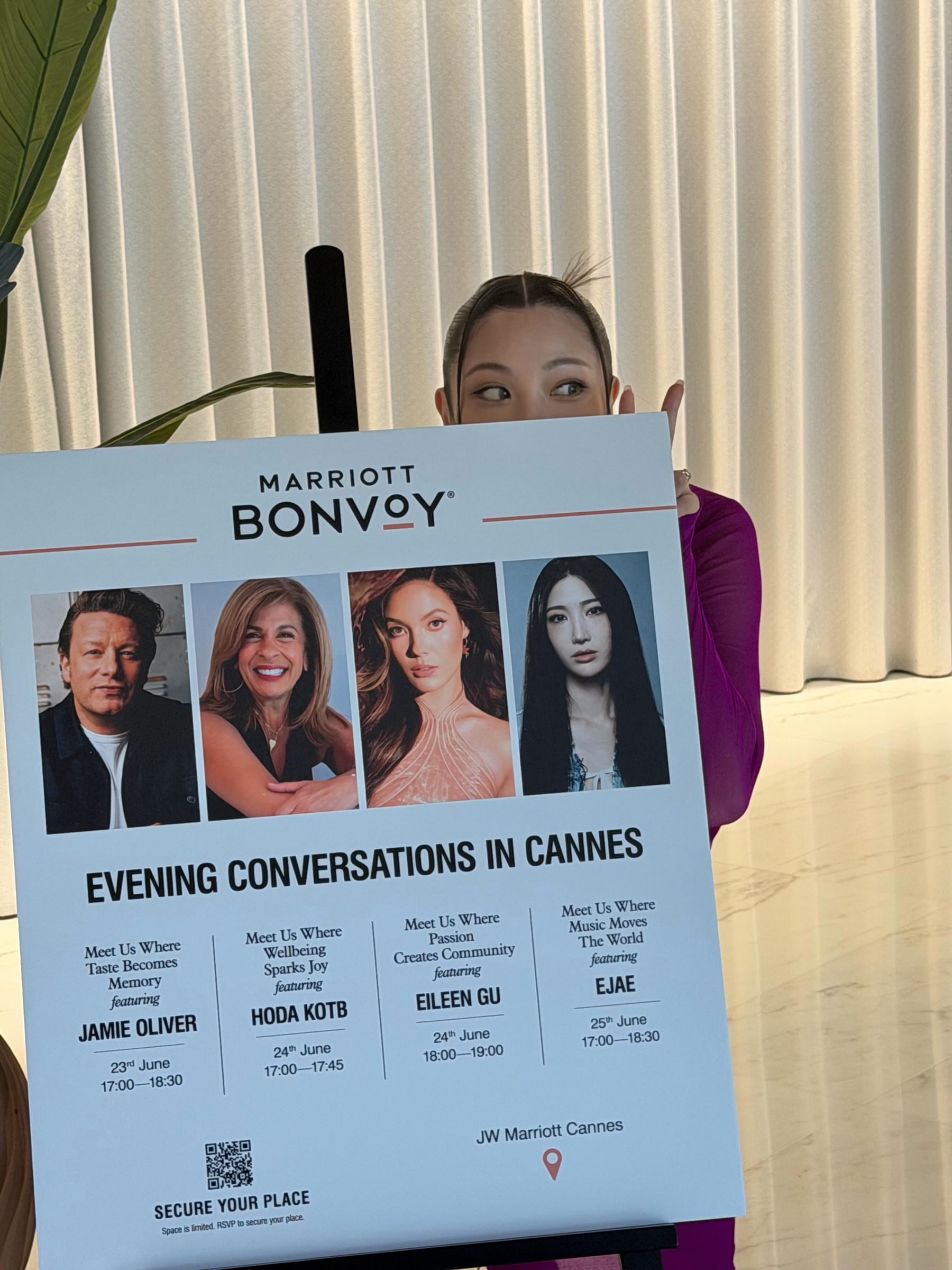 EJAE peeking from behind the Evening Conversations in Cannes easel poster