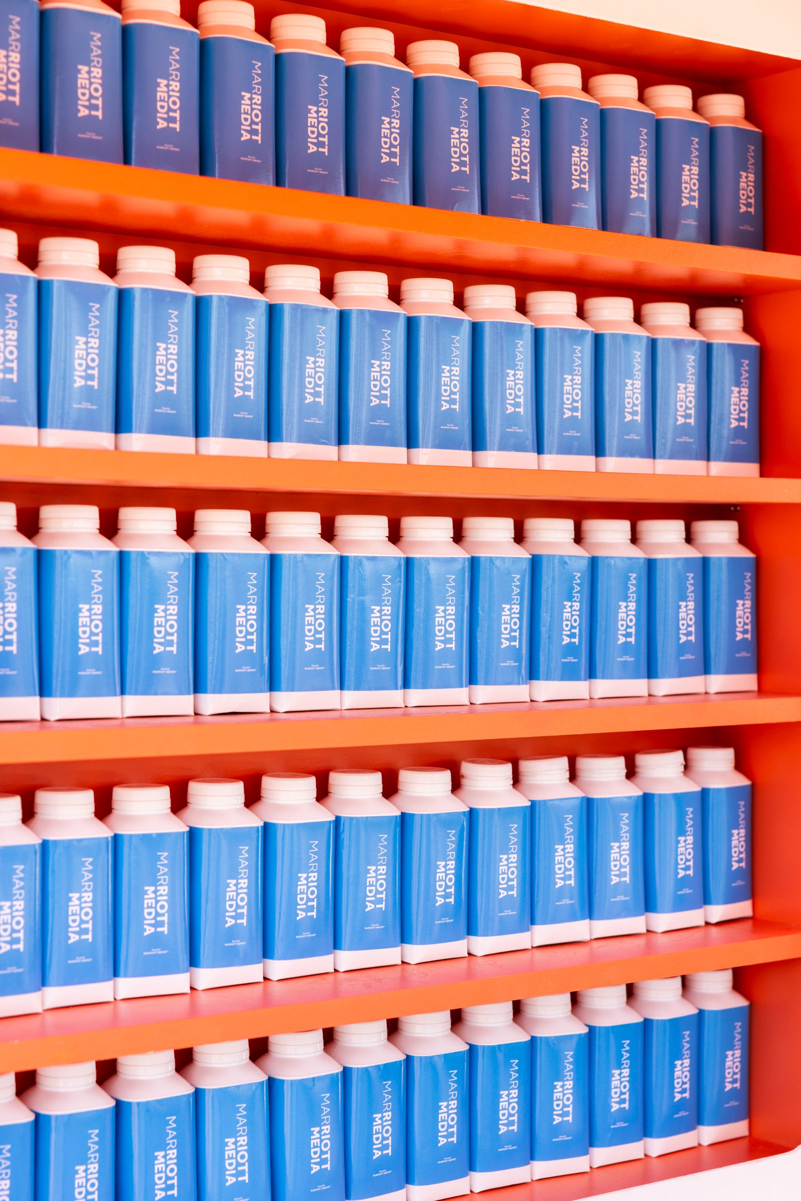 Rows of Marriott Media water bottles on orange shelves