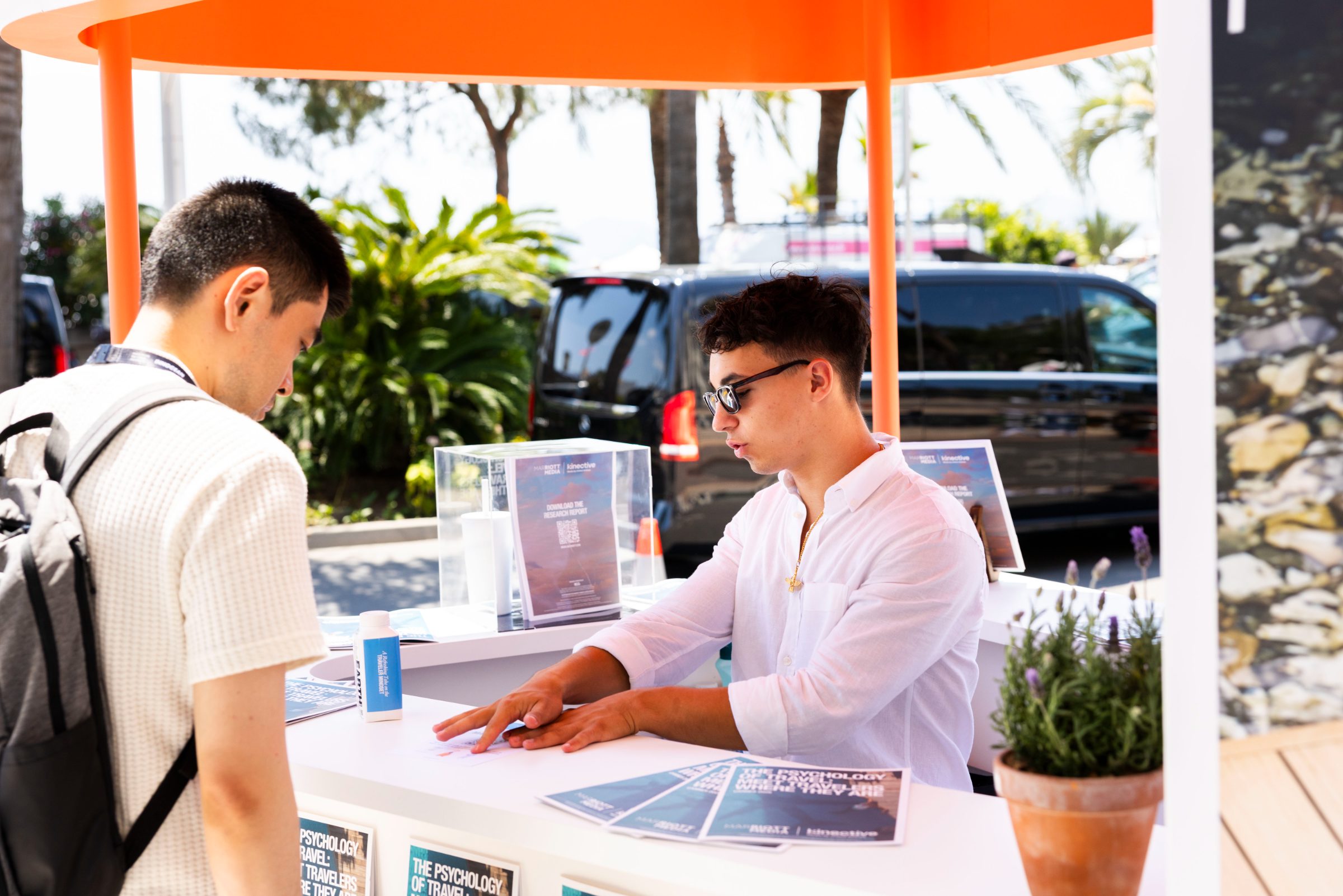 Newsstand staff handing a branded fan to a guest