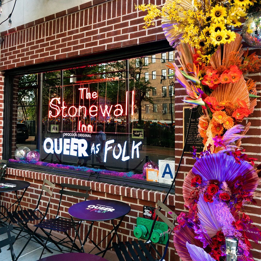 Queer As Folk and Stonewall Inn neon signage in the decorated storefront