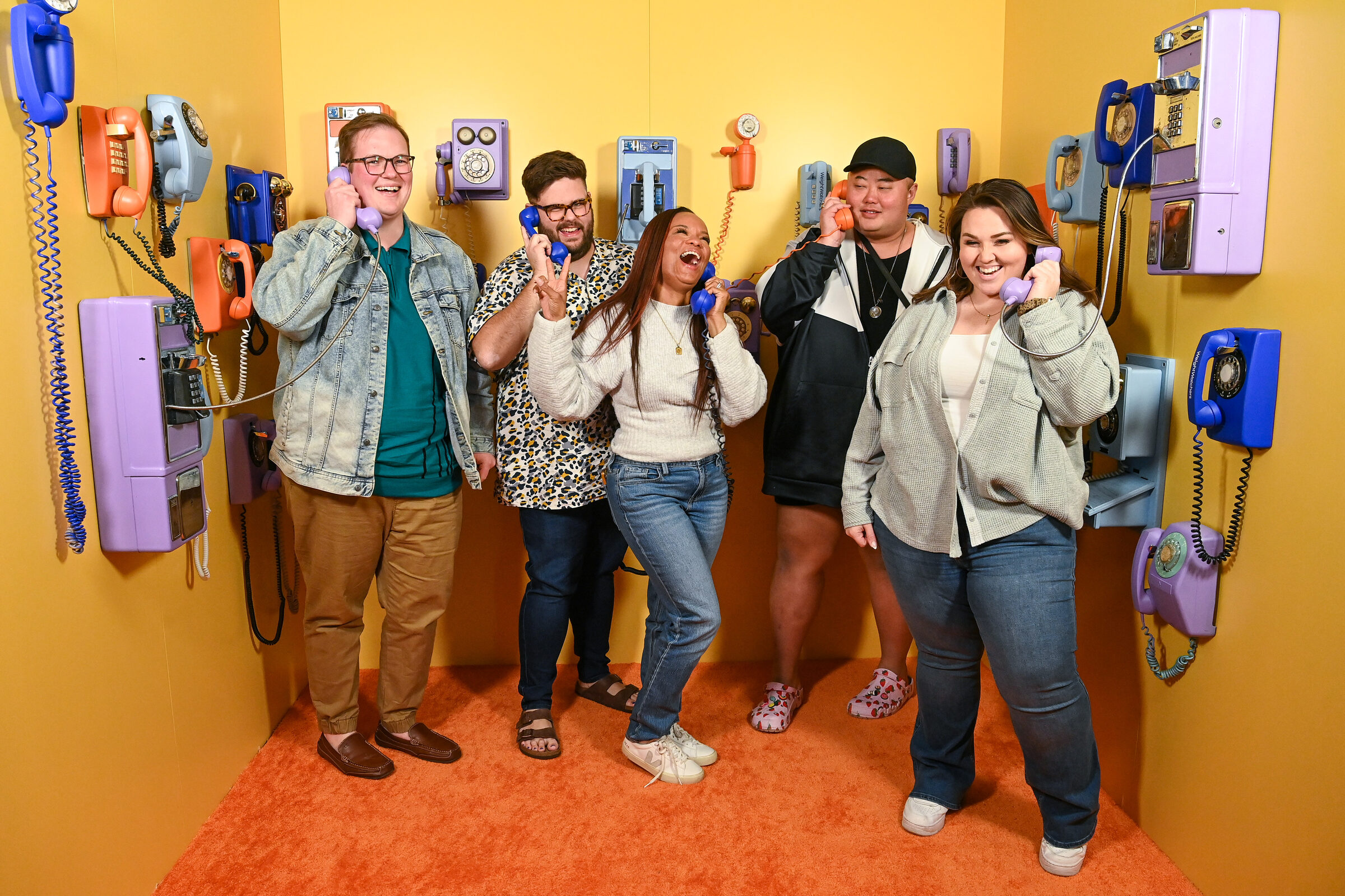 Creators posing with vintage handsets in the phone-covered Food Noise room