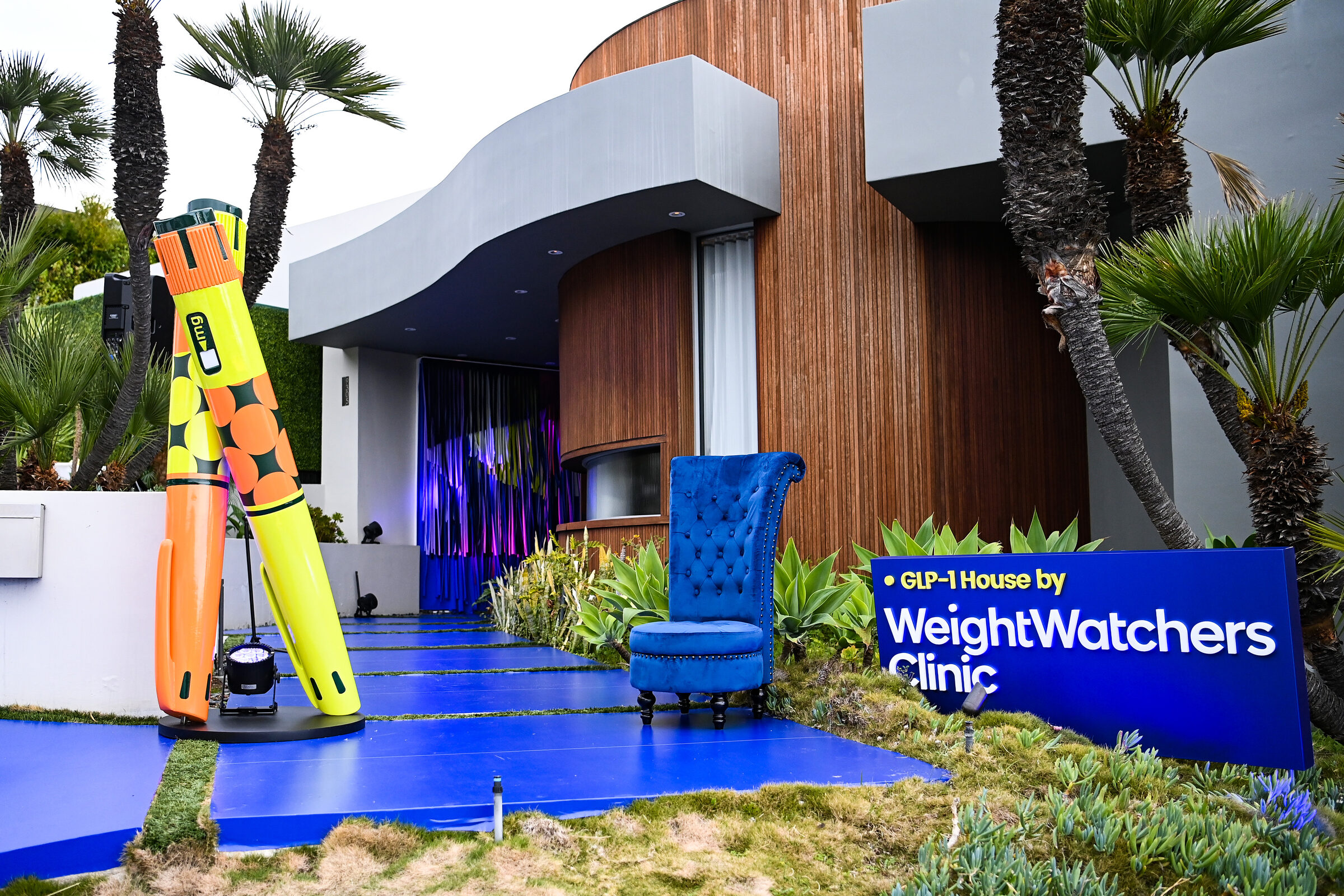 The GLP-1 House entrance — a blurple carpet, royal-blue throne and oversized GLP-1 pens outside a Hollywood Hills home
