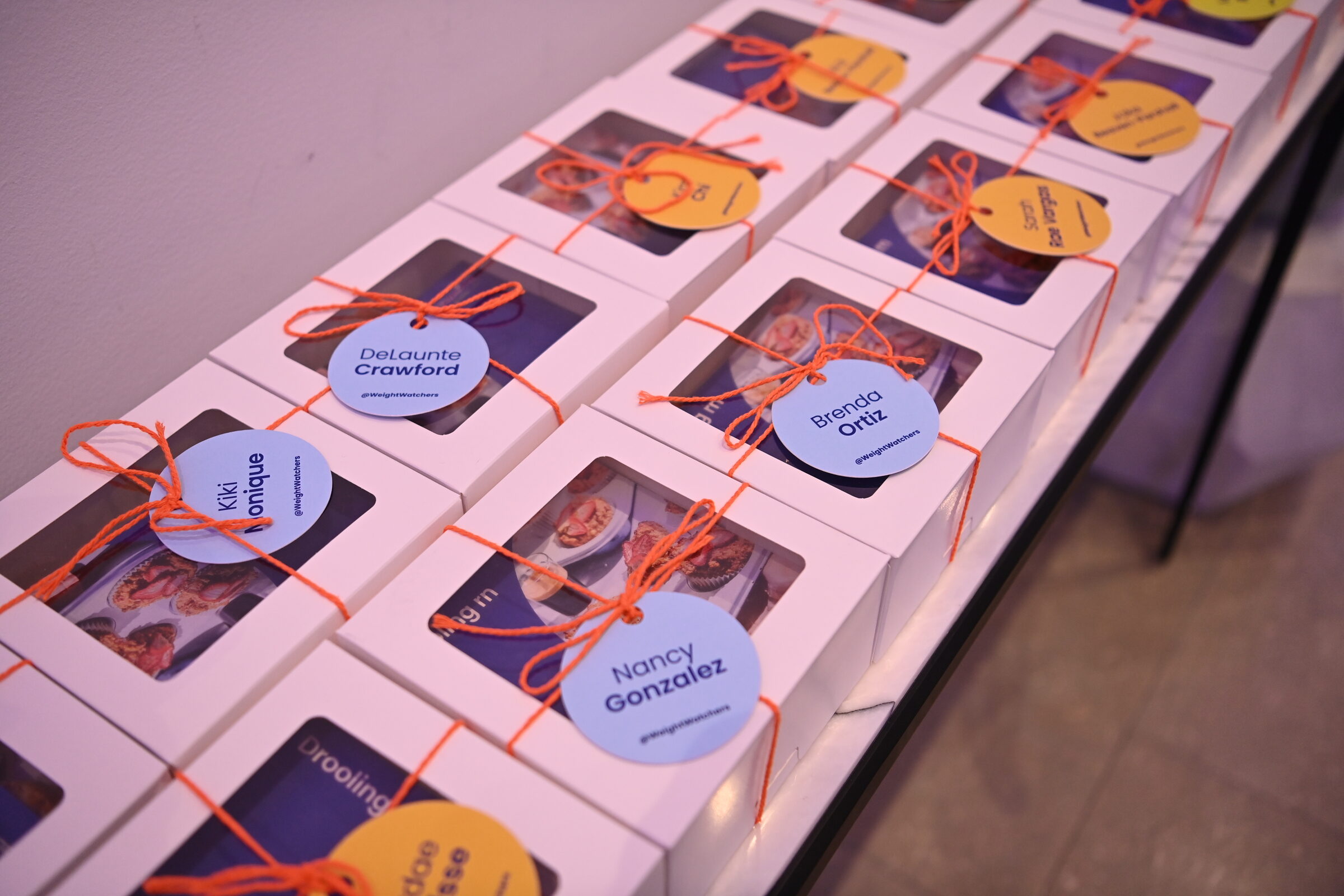 Personalized cookie takeaway boxes tied with orange ribbon
