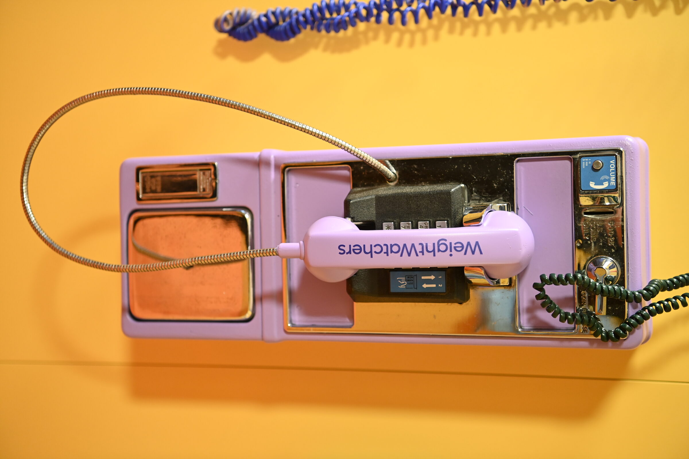 A lavender payphone with a WeightWatchers-branded handset cord
